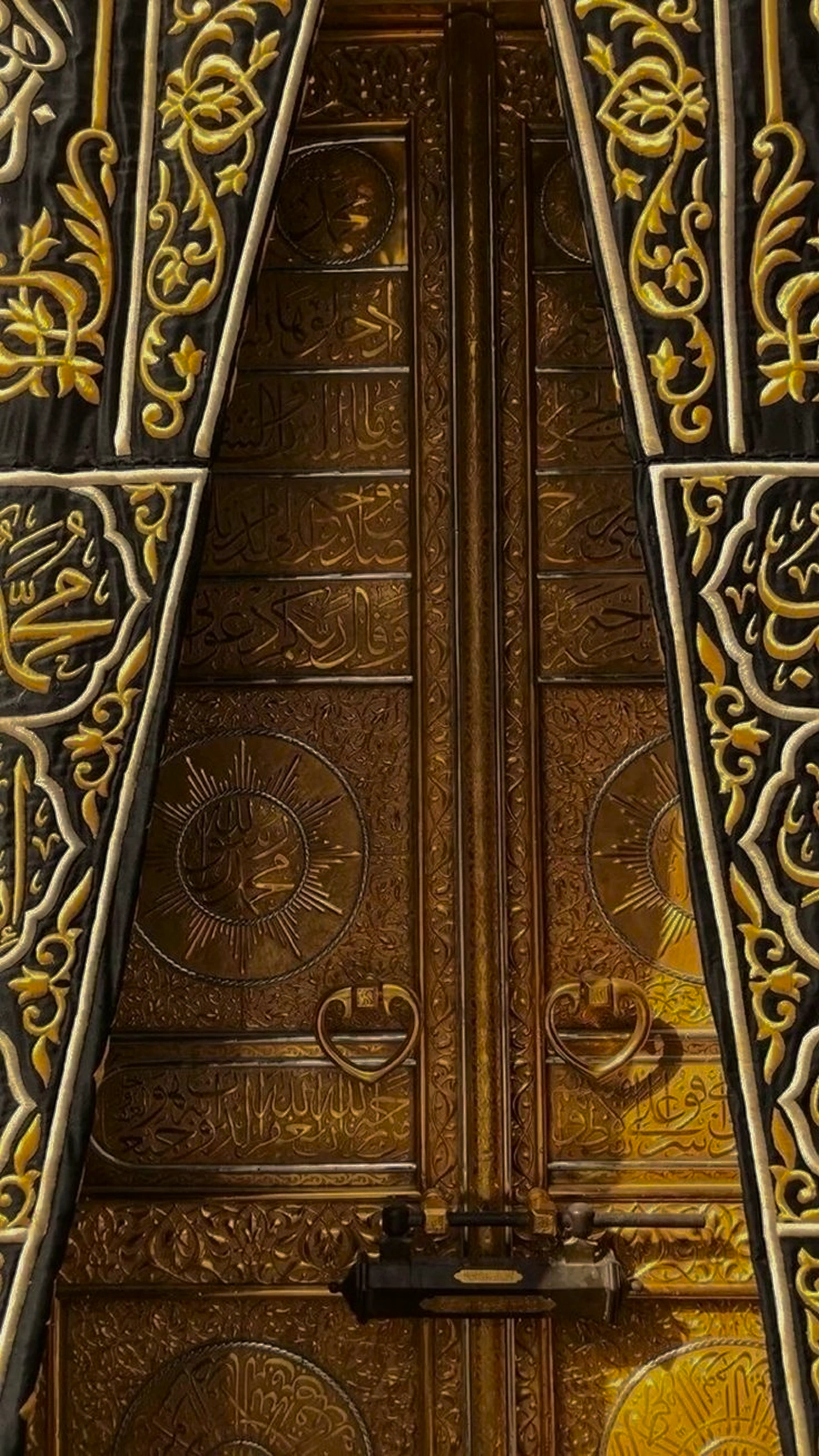 Close-up of the Kaaba's golden door, its leaves covered in raised Arabic calligraphy and framed by the embroidered curtain.