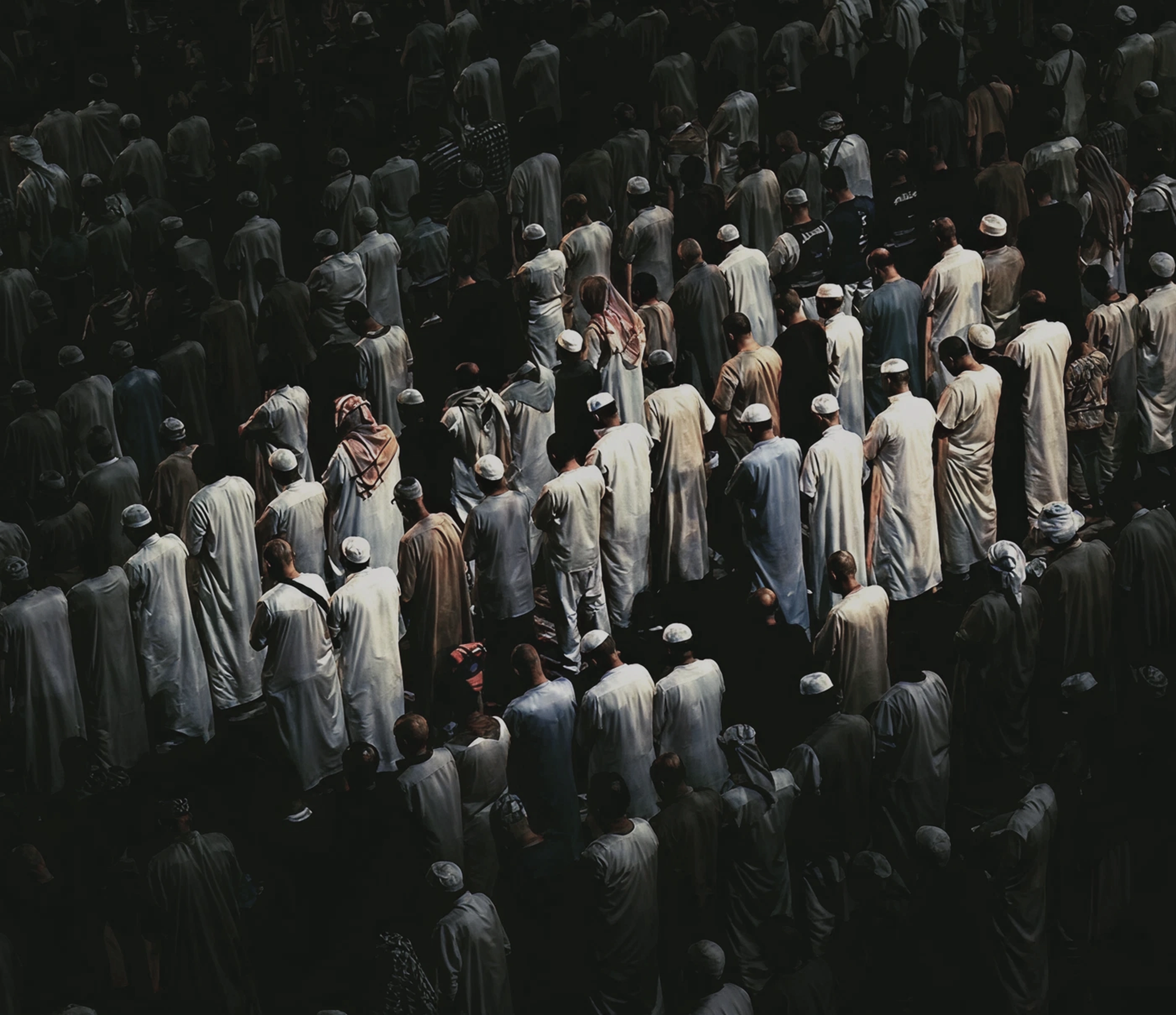 Dense rows of worshippers stand shoulder to shoulder in prayer, seen from above.