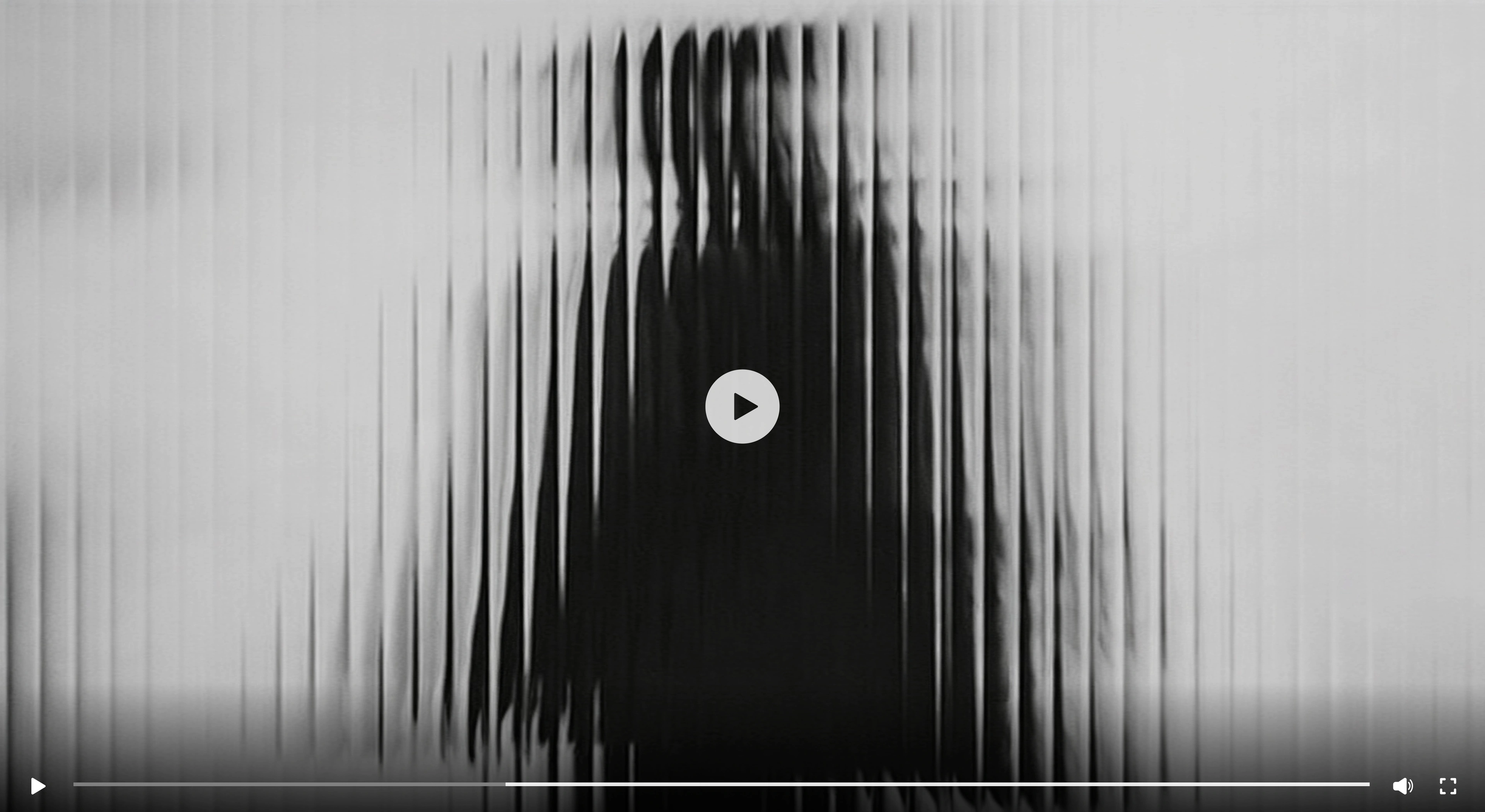 A grainy black and white still from the Saudi Formation Partners brand film, long vertical motion-blur streaks running across the frame behind a circular play button and a video transport bar.