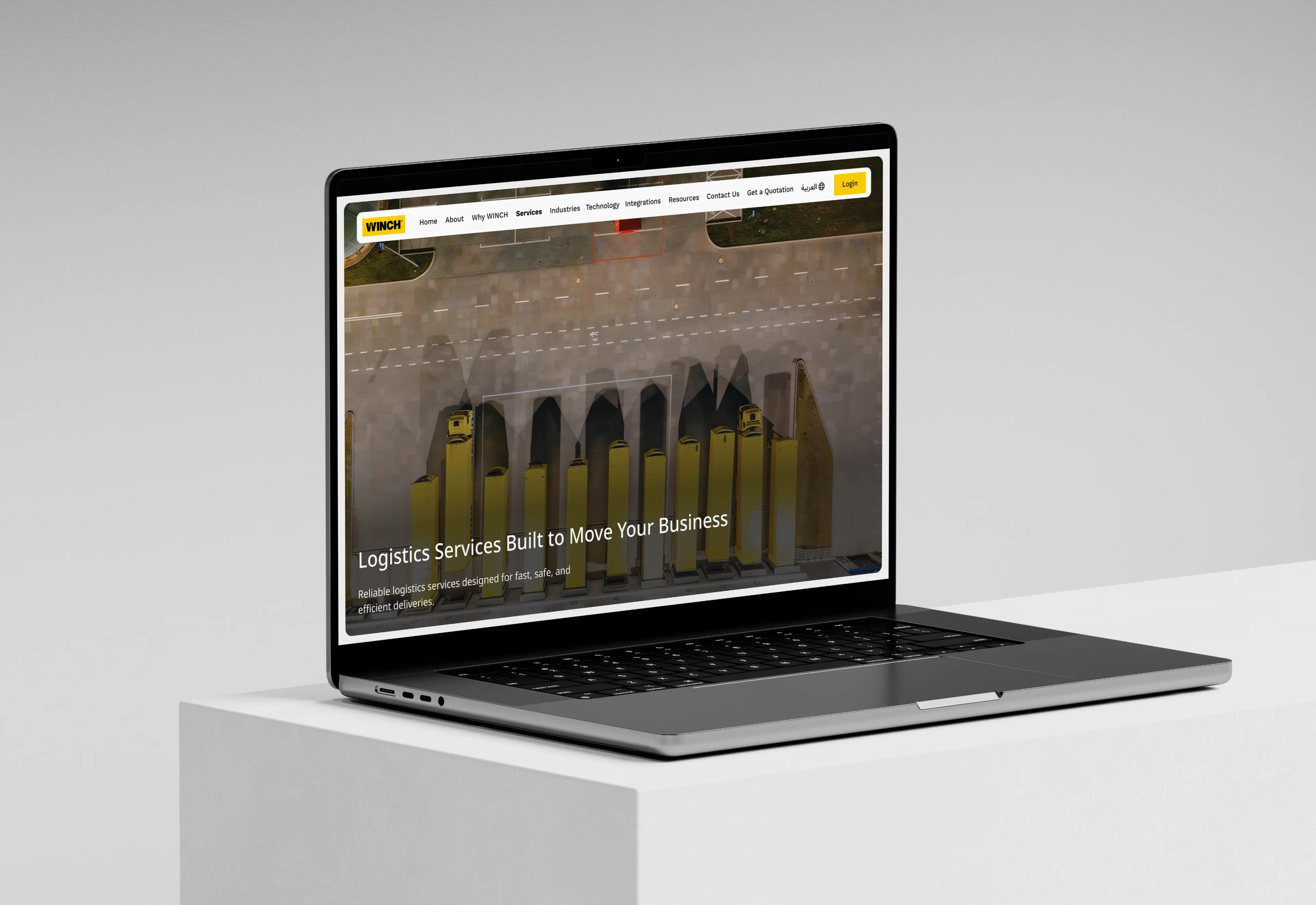 A laptop at a three-quarter angle showing the WINCH services page, headed Logistics Services Built to Move Your Business over a pale aerial view of a logistics yard where yellow WINCH trucks are parked nose-in across a concrete apron.