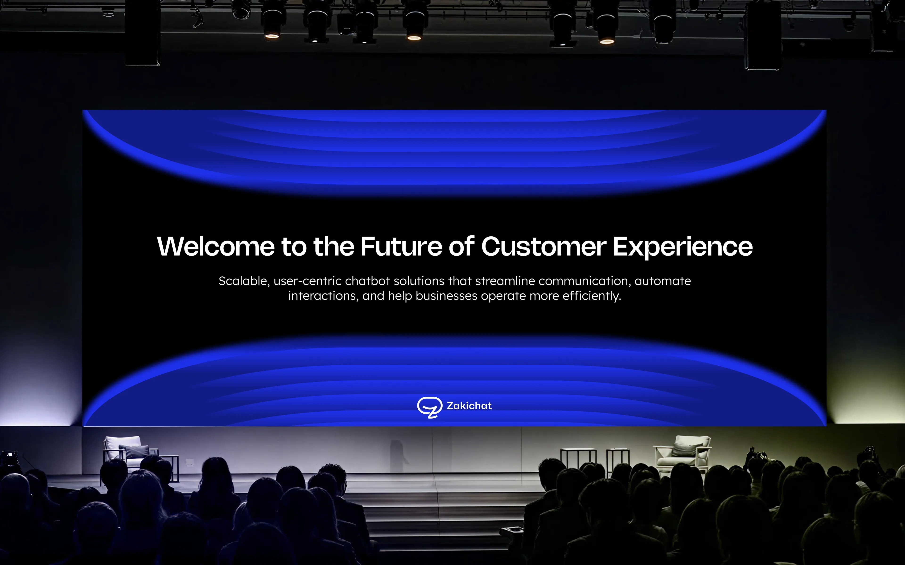 A darkened auditorium seen over silhouetted audience heads toward a wide LED stage screen showing Welcome to the Future of Customer Experience with a two-line subhead and the Zakichat lockup beneath.